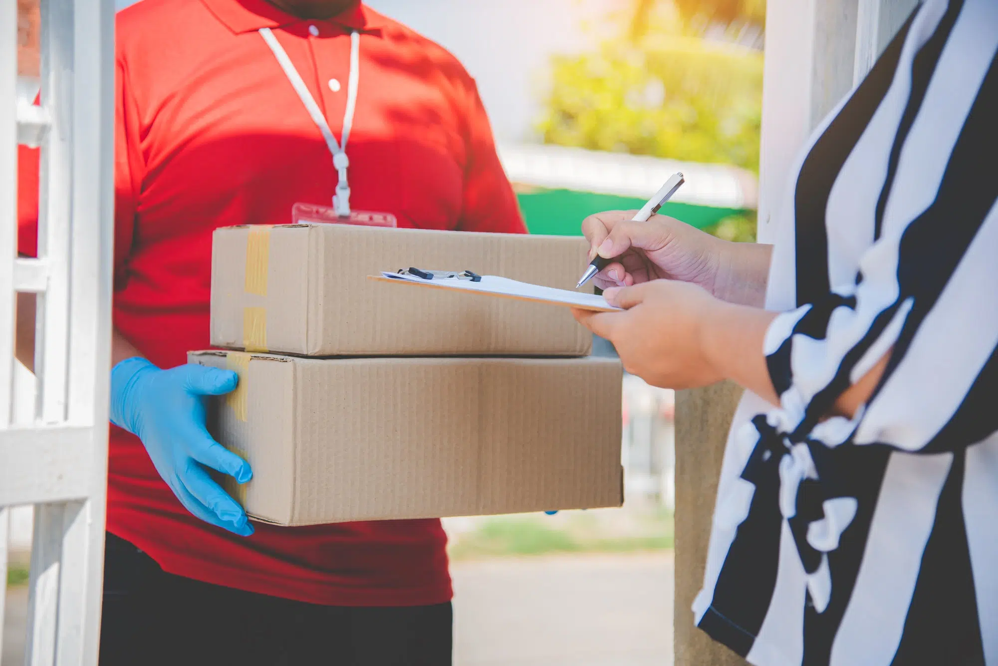 consumer is signing a document to receive a parcel from a home courier.