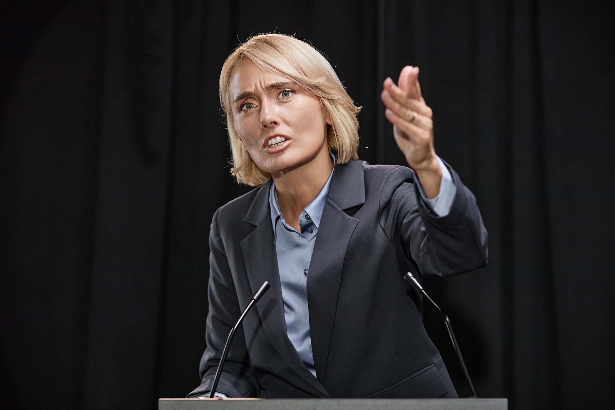 Female Politician Pointing at Public Giving Inspirational Speech while Standing on Stage Indoors