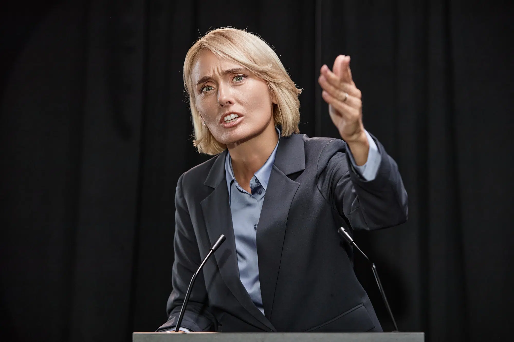 Female Politician Pointing at Public Giving Inspirational Speech while Standing on Stage Indoors